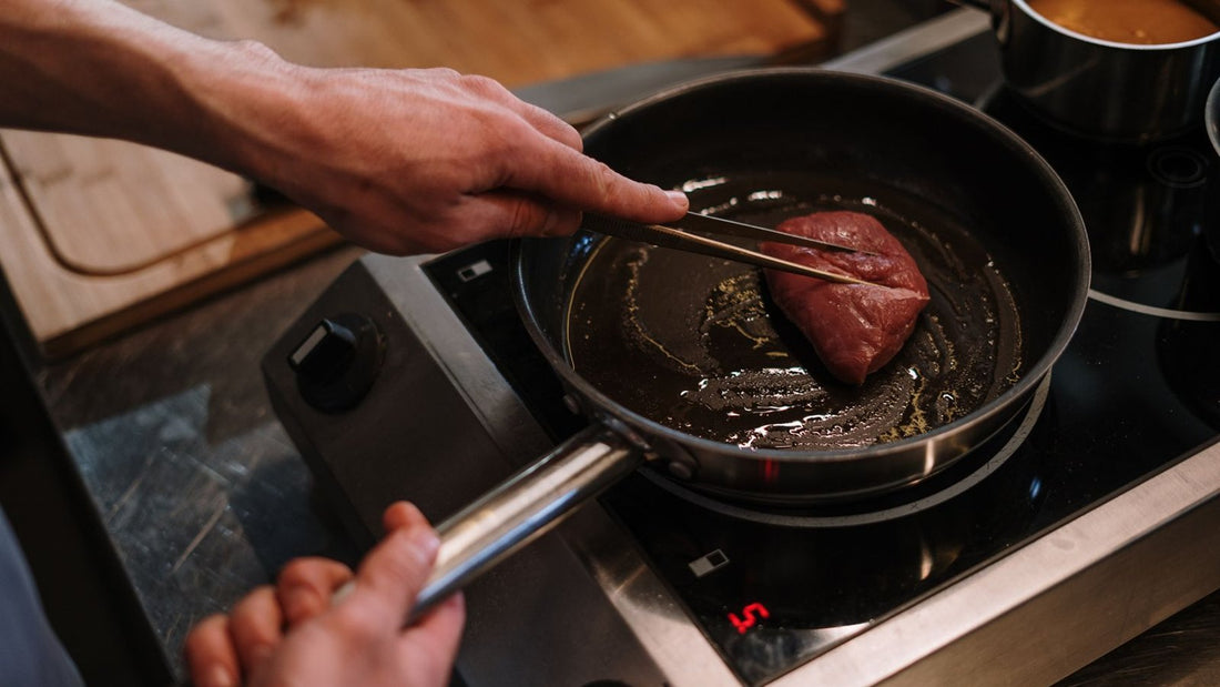 Chef saisissant une pièce de viande à la poêle sur induction