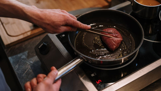 Chef saisissant une pièce de viande à la poêle sur induction